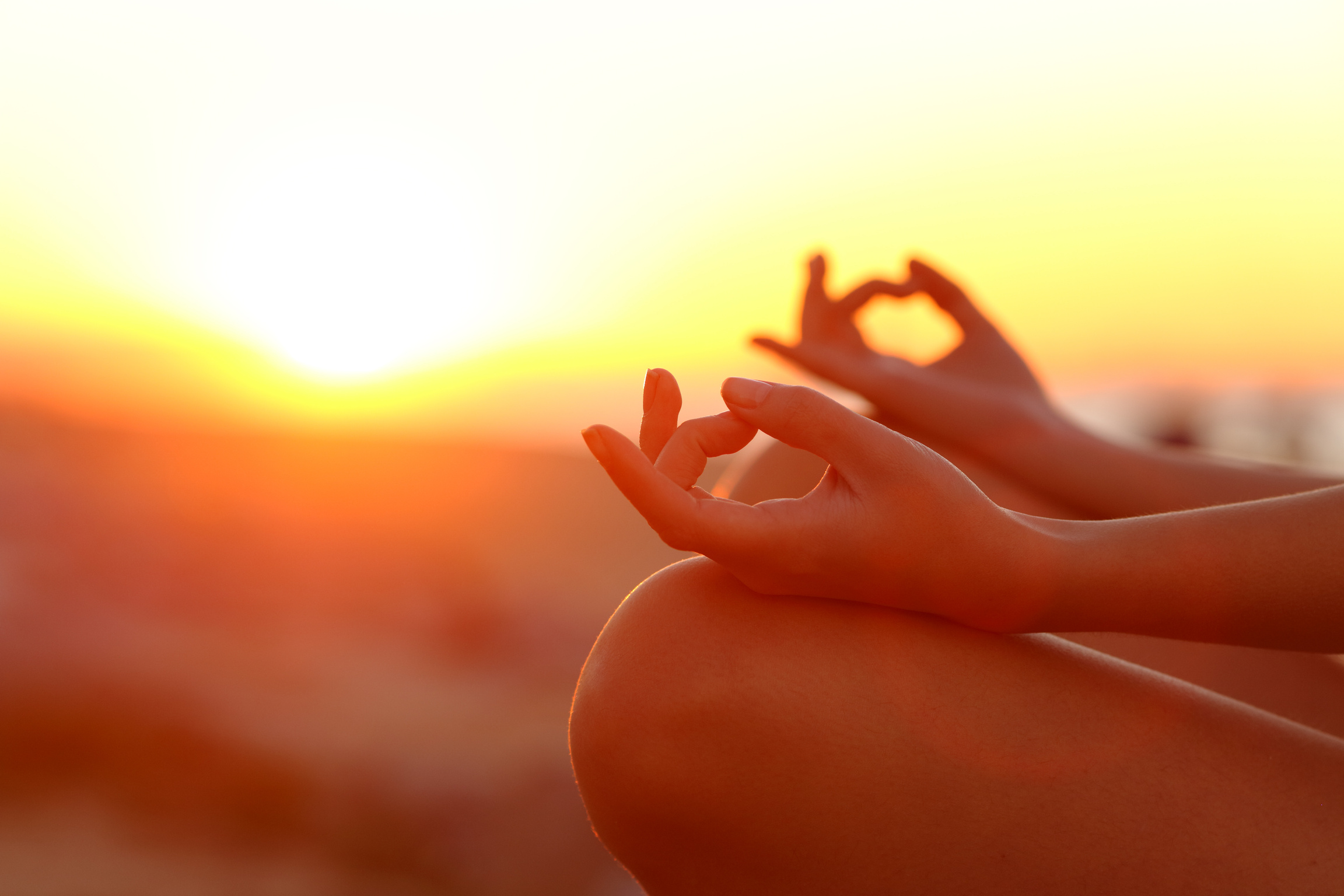 Woman hands doing yoga exercise at sunset